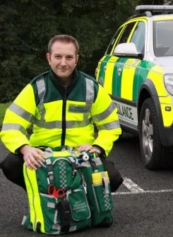 A Community Responder in uniform next to a CFR Car