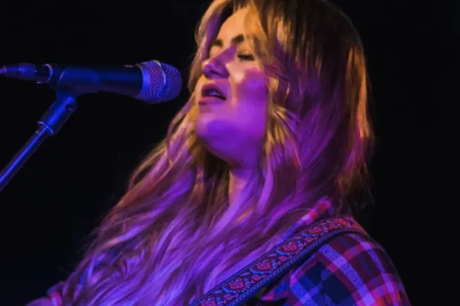 a photo of Meg Fox signing into a microphone on a stand.