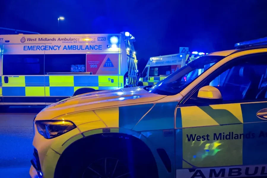 Ambulance van in the background, an ambulance car in the foreground - at night time with blue lights on