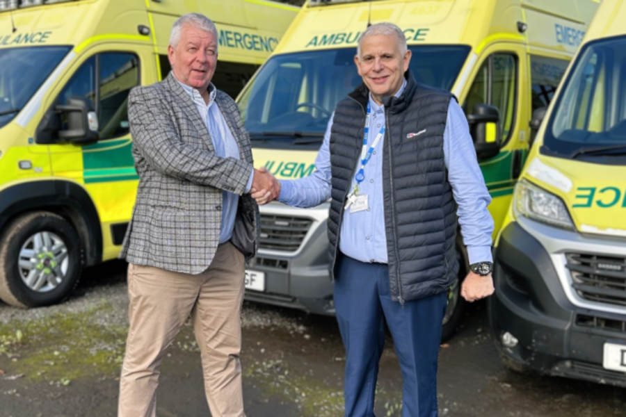 two men shaking hands in front of ambulances