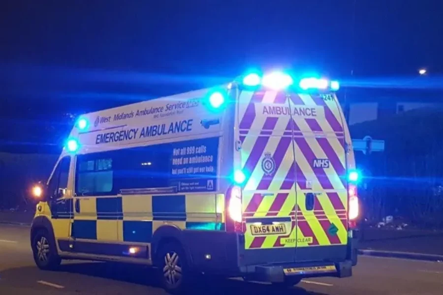 ambulance travelling on a road at night with blue lights on