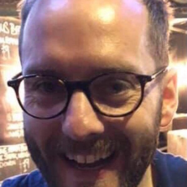 a close up of a smiling man wearing glasses