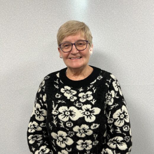 A lady in a floral top in front of a white wall