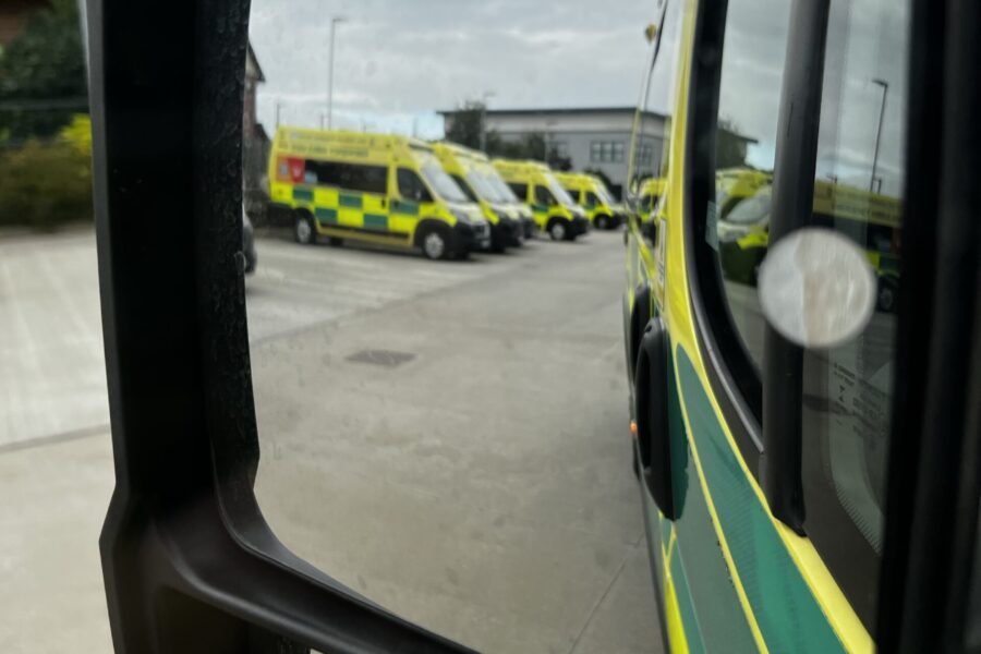 Reflection of side of ambulance through side mirror with row of ambulances parked up